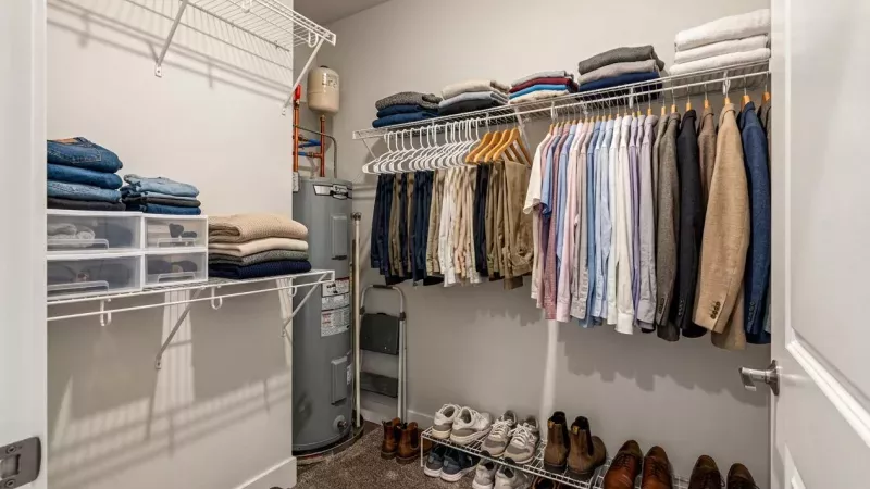 Organized walk-in closet with shelves, hanging clothes, many shoes.