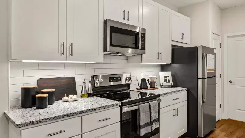 Modern kitchen featuring white cabinets, subway tile, stainless steel appliances, and granite countertops.