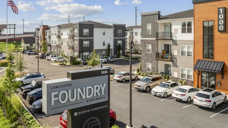Elevated view of modern Lancaster Foundry Apartments, with several multi-story buildings, a prominent sign, and parking.