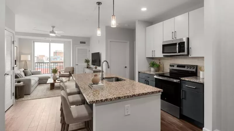 Modern open-concept living space with a kitchen island, white and grey cabinets, and a connected living room.