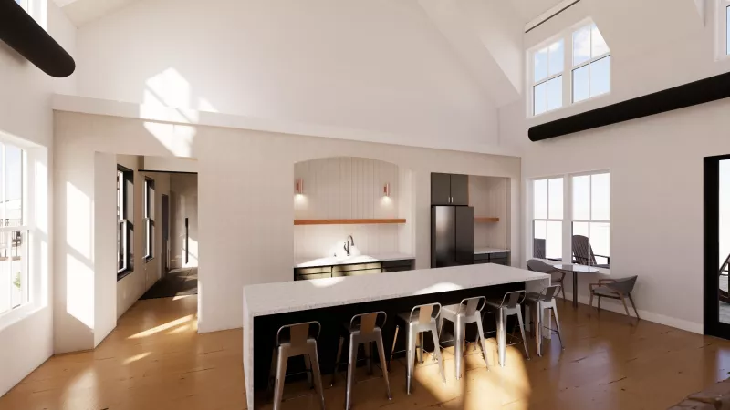 Modern open-plan clubhouse kitchen with a large island, bar stools, vaulted ceilings, and sunny wooden floors.