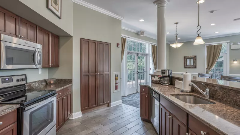Modern communal kitchen with dark wood cabinets, granite counters, stainless steel appliances, and an open layout.