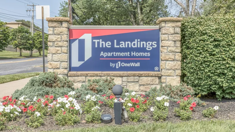 Monument sign for The Landings Apartment Homes, surrounded by colorful flowers and greenery.