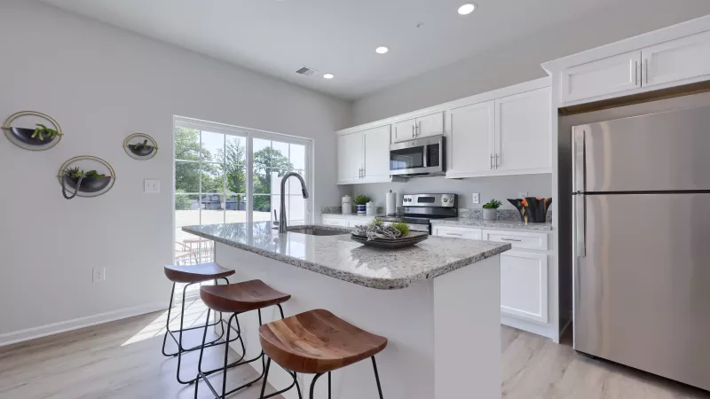 Modern kitchen with granite island, wood barstools, and a large window offering plenty of natural light