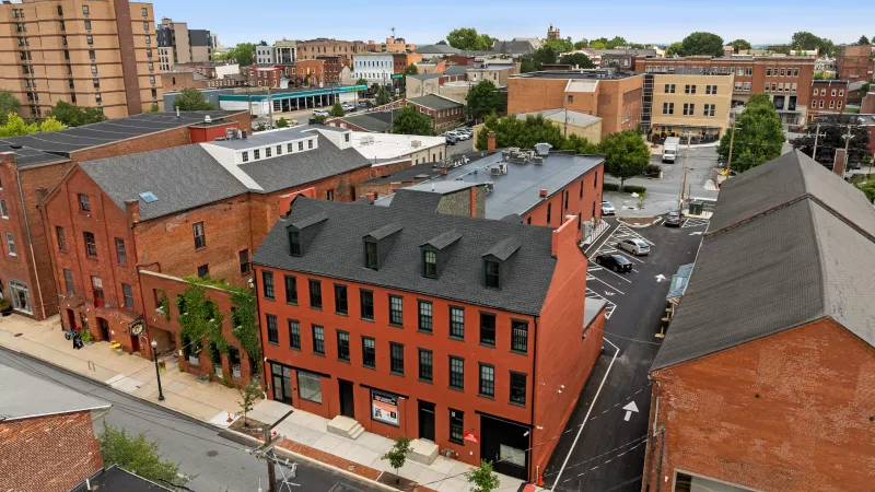 Aerial view of Prince Street Lofts in Downtown Lancaster, PA, showcasing the red-brick façade, rooftop dormers, and surrounding historic architecture.