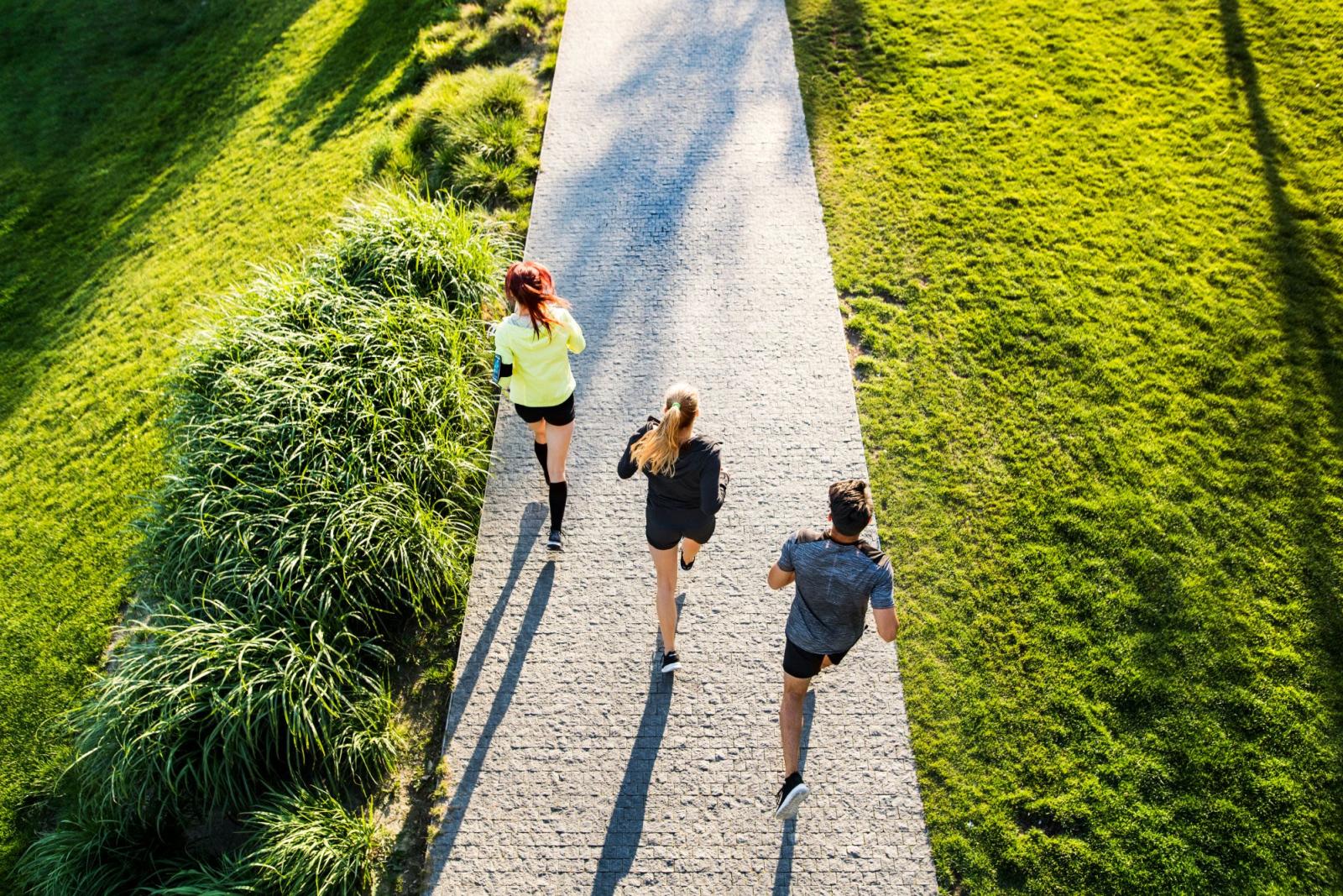 Three people jogging through a park