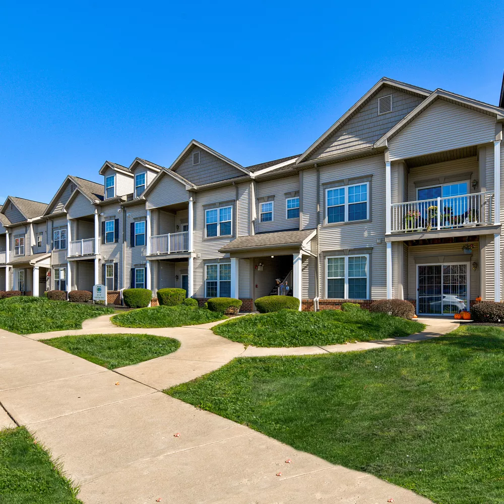 Row of apartment homes with covered entrances, balconies, and well-maintained pathways at Newport Commons.