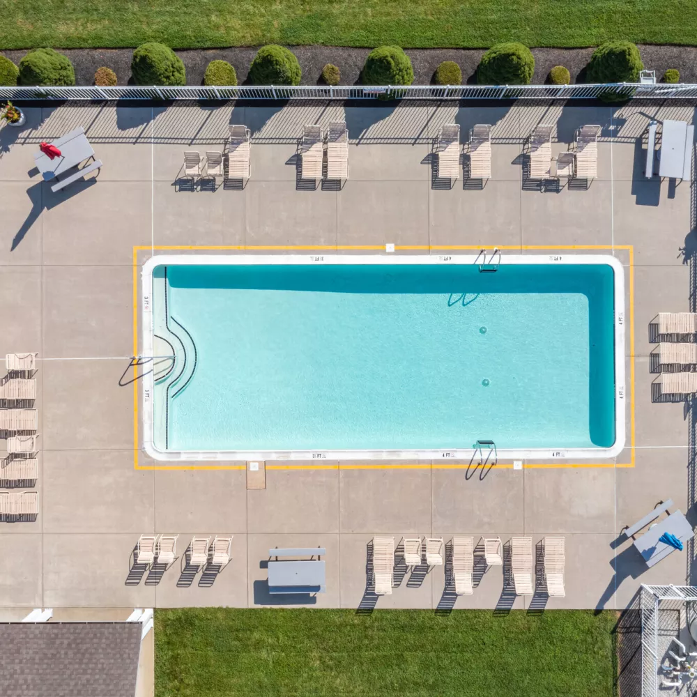 Aerial view of Newport Commons community pool area with surrounding lounge chairs and neatly landscaped green space.