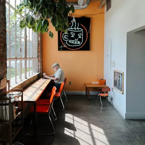 open, colorful cafe with an individual enjoying peace & quiet in the sunshine
