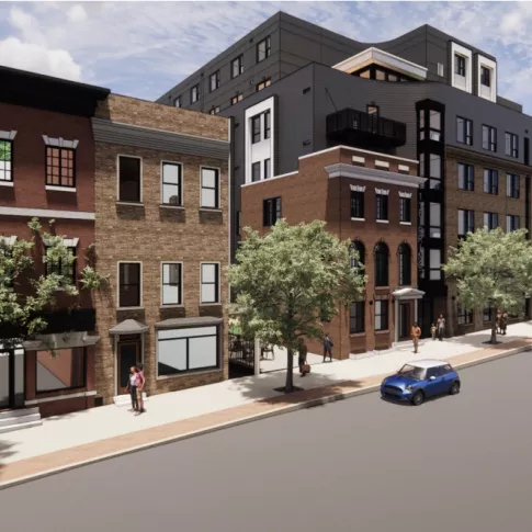 Wide-angle street scene showing historic rowhomes and the newer apartment building blending into the surrounding neighborhood.