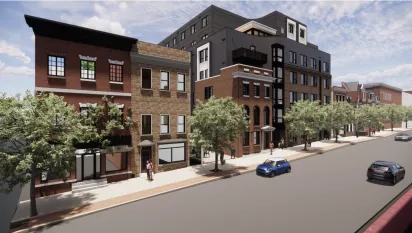 Wide-angle street scene showing historic rowhomes and the newer apartment building blending into the surrounding neighborhood.