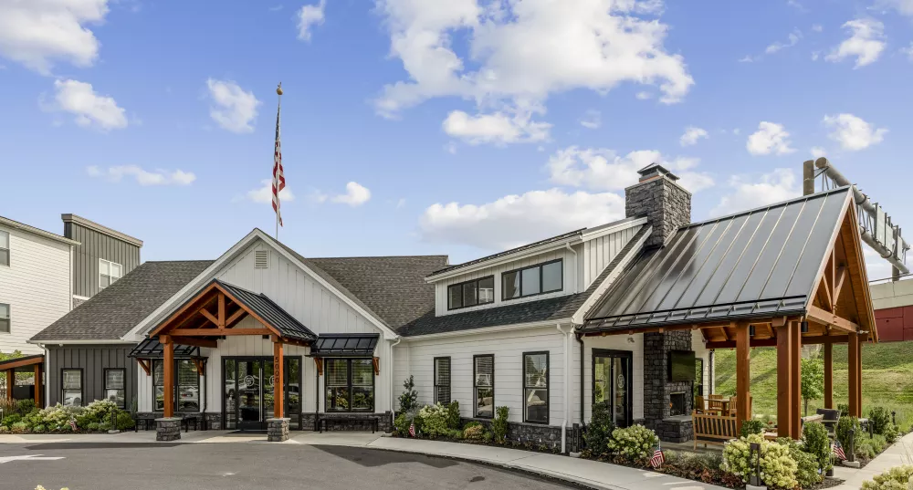 Modern farmhouse-style building with white and dark gray siding, wooden accents, and an American flag.
