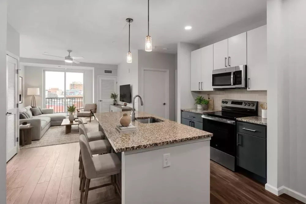 Modern open-concept living space with a kitchen island, white and grey cabinets, and a connected living room.