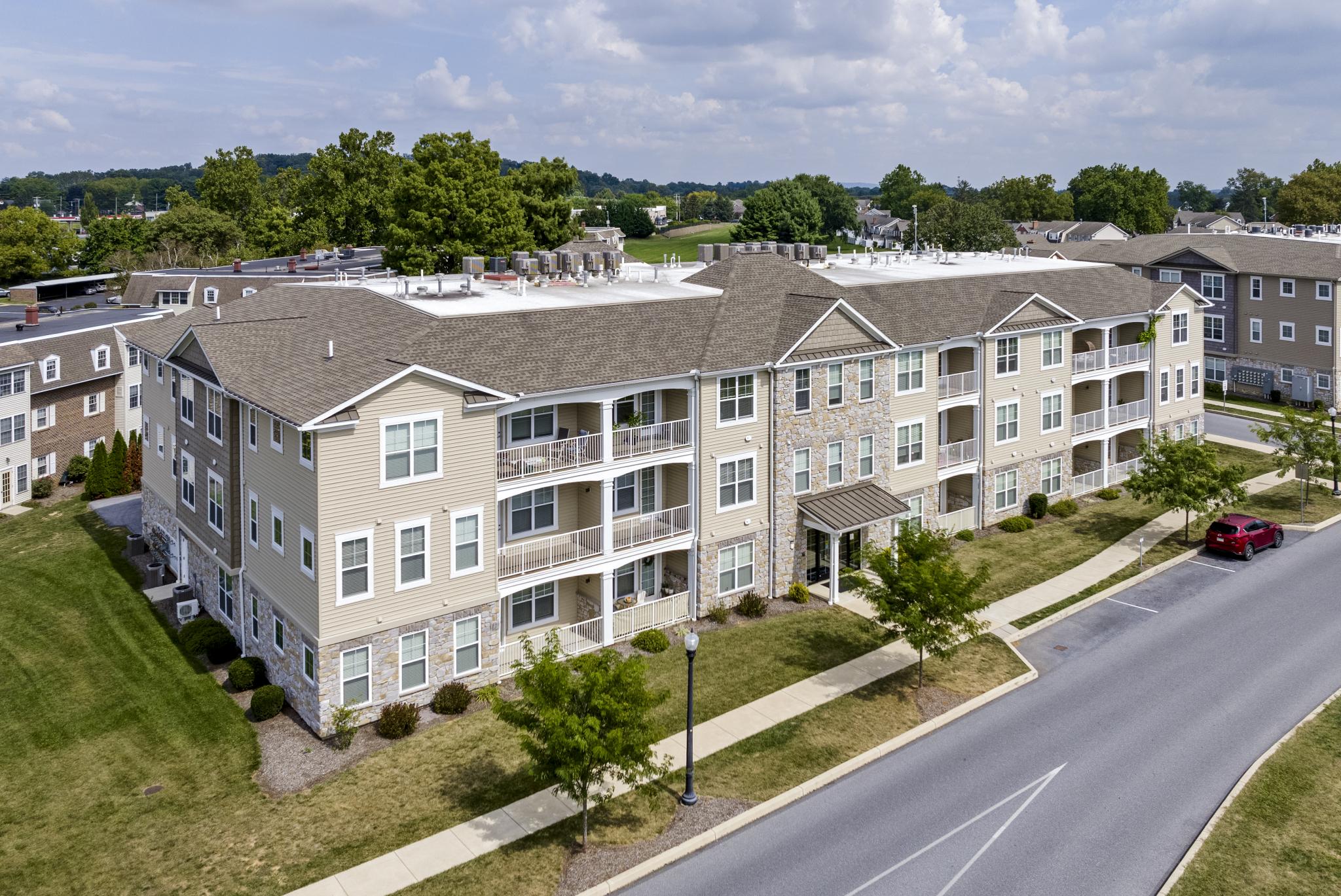 Apartment building exterior with multiple stories, brick detailing, and manicured lawns.