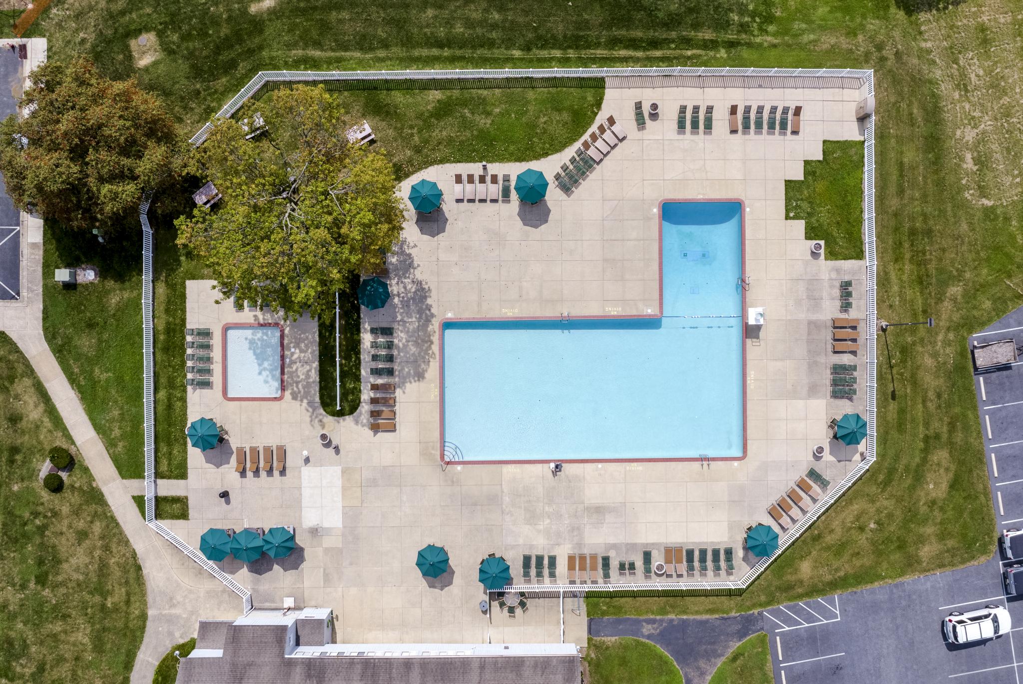 Overhead view of resort-style pool area with lounge seating, umbrellas, and a separate kiddie pool section.