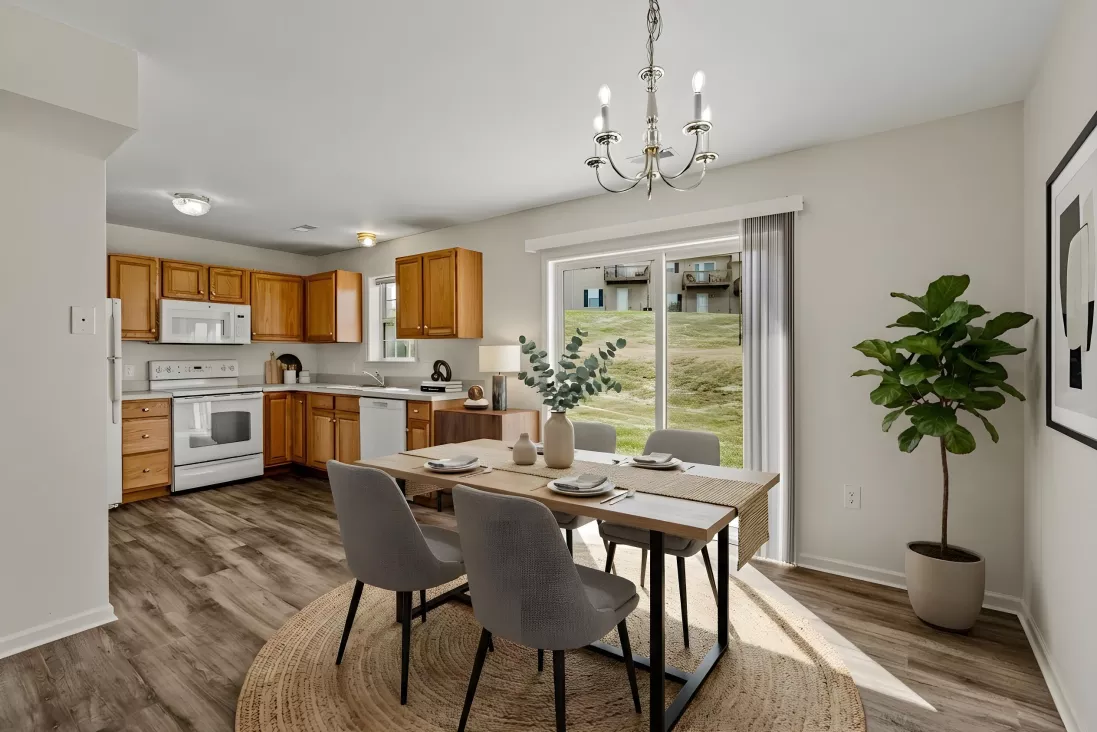 Open-concept kitchen with light wood cabinets, white appliances, dining table with chairs, and a sliding door.